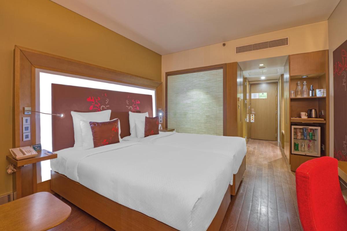 a bedroom with a large white bed and a red chair at Novotel Bengaluru Outer Ring Road in Bengaluru