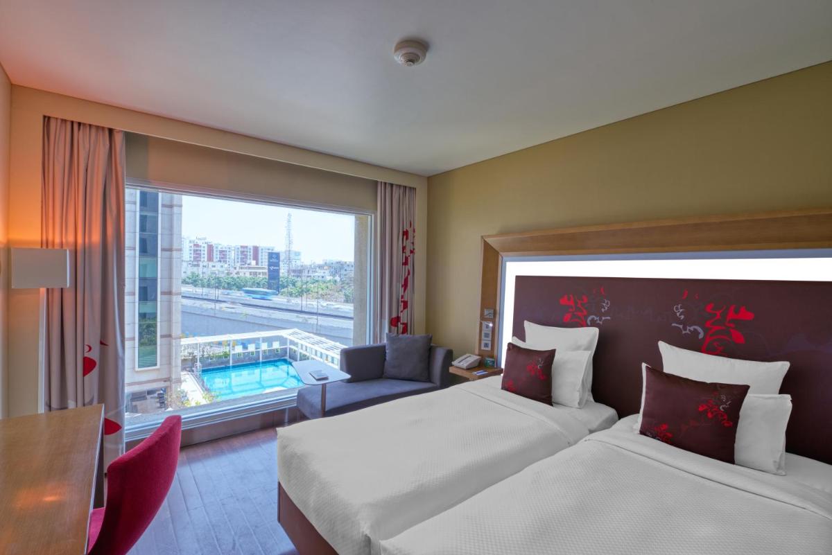 a hotel room with two beds and a window at Novotel Bengaluru Outer Ring Road in Bengaluru