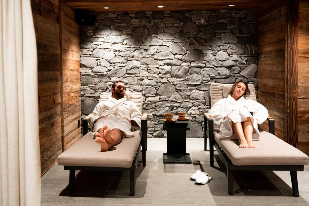 un homme et une femme assis sur des chaises dans un spa dans l'établissement Hôtel Névé, à Morzine