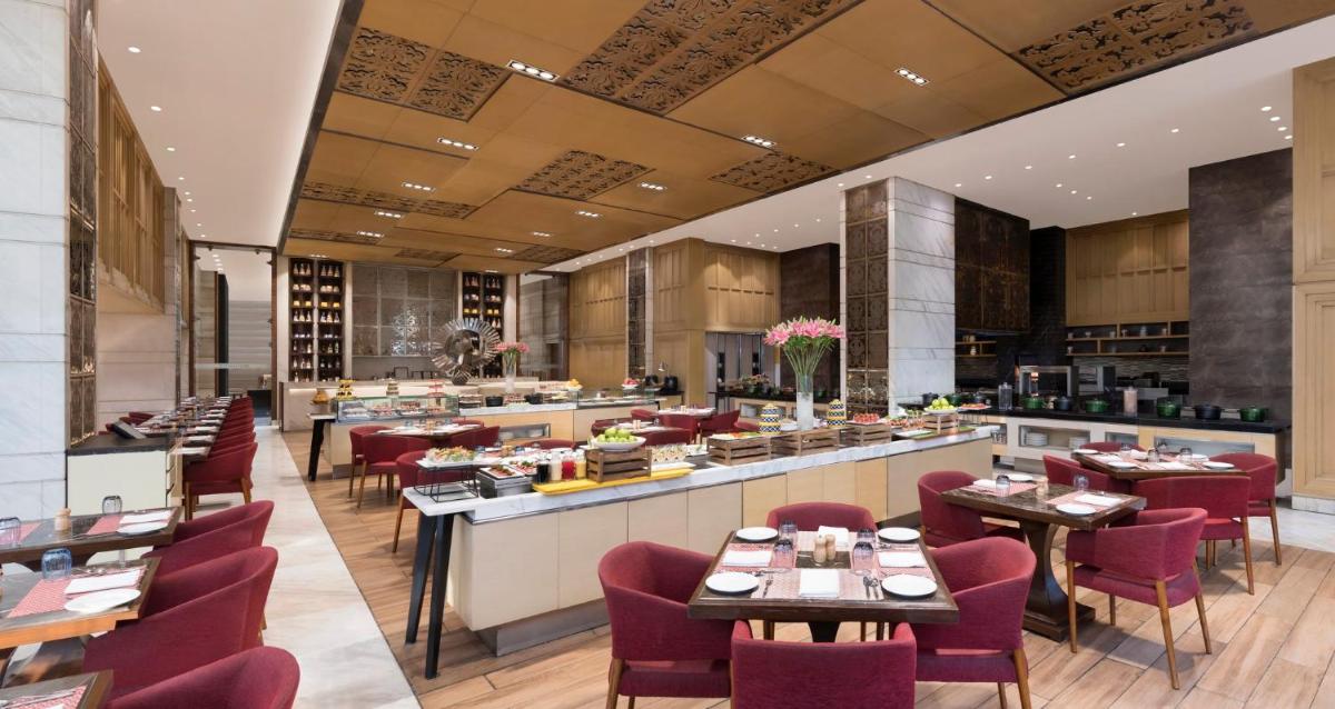 a restaurant with tables and chairs and a bar at Crowne Plaza New Delhi Mayur Vihar Noida by IHG in New Delhi