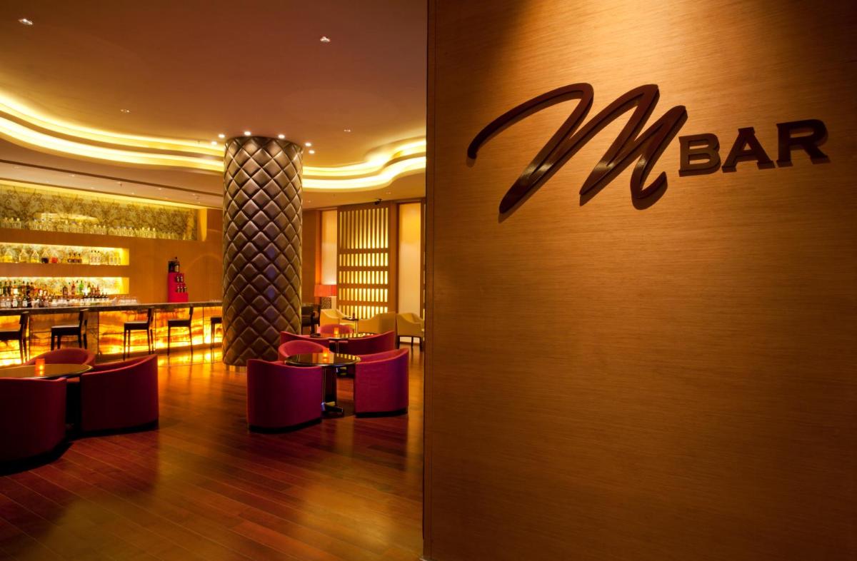 a bar in a restaurant with a sign on the wall at Bengaluru Marriott Hotel Whitefield in Bengaluru