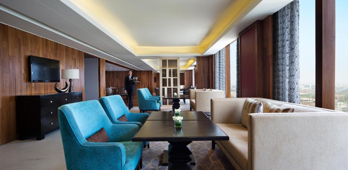 a hotel room with blue chairs and a table at Bengaluru Marriott Hotel Whitefield in Bengaluru a hotel room with blue chairs and a table at Bengaluru Marriott Hotel Whitefield in Bengaluru