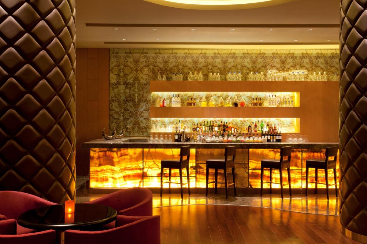 a bar in a restaurant with a fireplace at Bengaluru Marriott Hotel Whitefield in Bengaluru