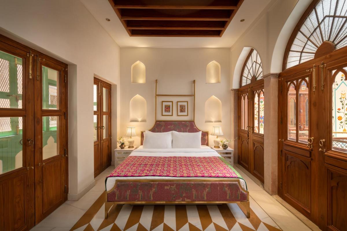 a bedroom with a bed and two windows at Haveli Dharampura & Golden Haveli- UNESCO awarded Boutique Heritage Hotel in New Delhi a bedroom with a bed and two windows at Haveli Dharampura & Golden Haveli- UNESCO awarded Boutique Heritage Hotel in New Delhi