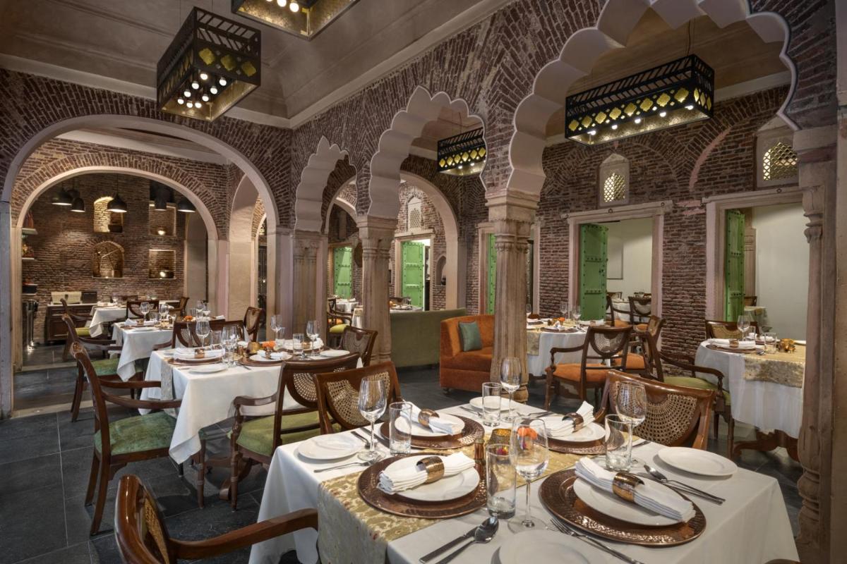 a restaurant with tables and chairs in a room at Haveli Dharampura & Golden Haveli- UNESCO awarded Boutique Heritage Hotel in New Delhi a restaurant with tables and chairs in a room at Haveli Dharampura & Golden Haveli- UNESCO awarded Boutique Heritage Hotel in New Delhi
