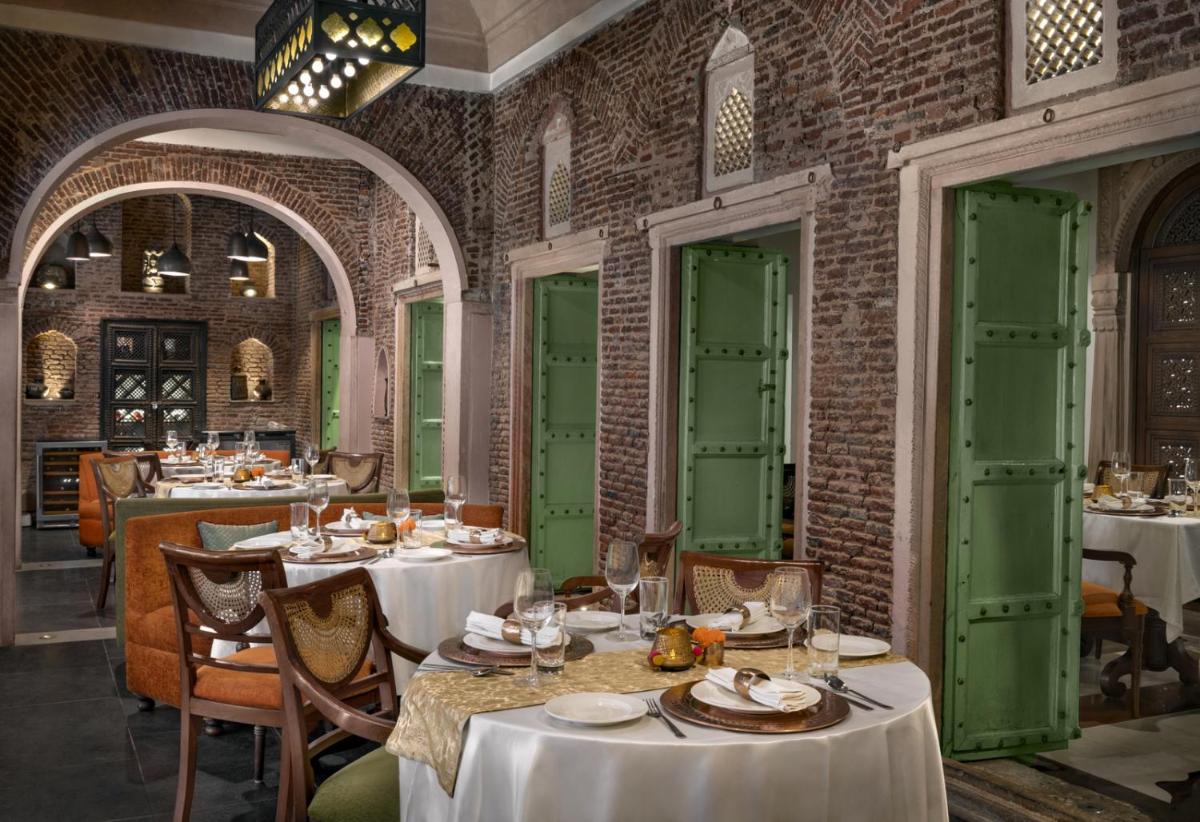 a restaurant with white tables and green doors at Haveli Dharampura & Golden Haveli- UNESCO awarded Boutique Heritage Hotel in New Delhi a restaurant with white tables and green doors at Haveli Dharampura & Golden Haveli- UNESCO awarded Boutique Heritage Hotel in New Delhi