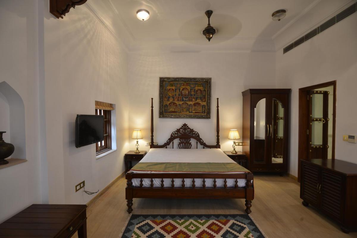 a bedroom with a bed and a flat screen tv at Haveli Dharampura & Golden Haveli- UNESCO awarded Boutique Heritage Hotel in New Delhi a bedroom with a bed and a flat screen tv at Haveli Dharampura & Golden Haveli- UNESCO awarded Boutique Heritage Hotel in New Delhi