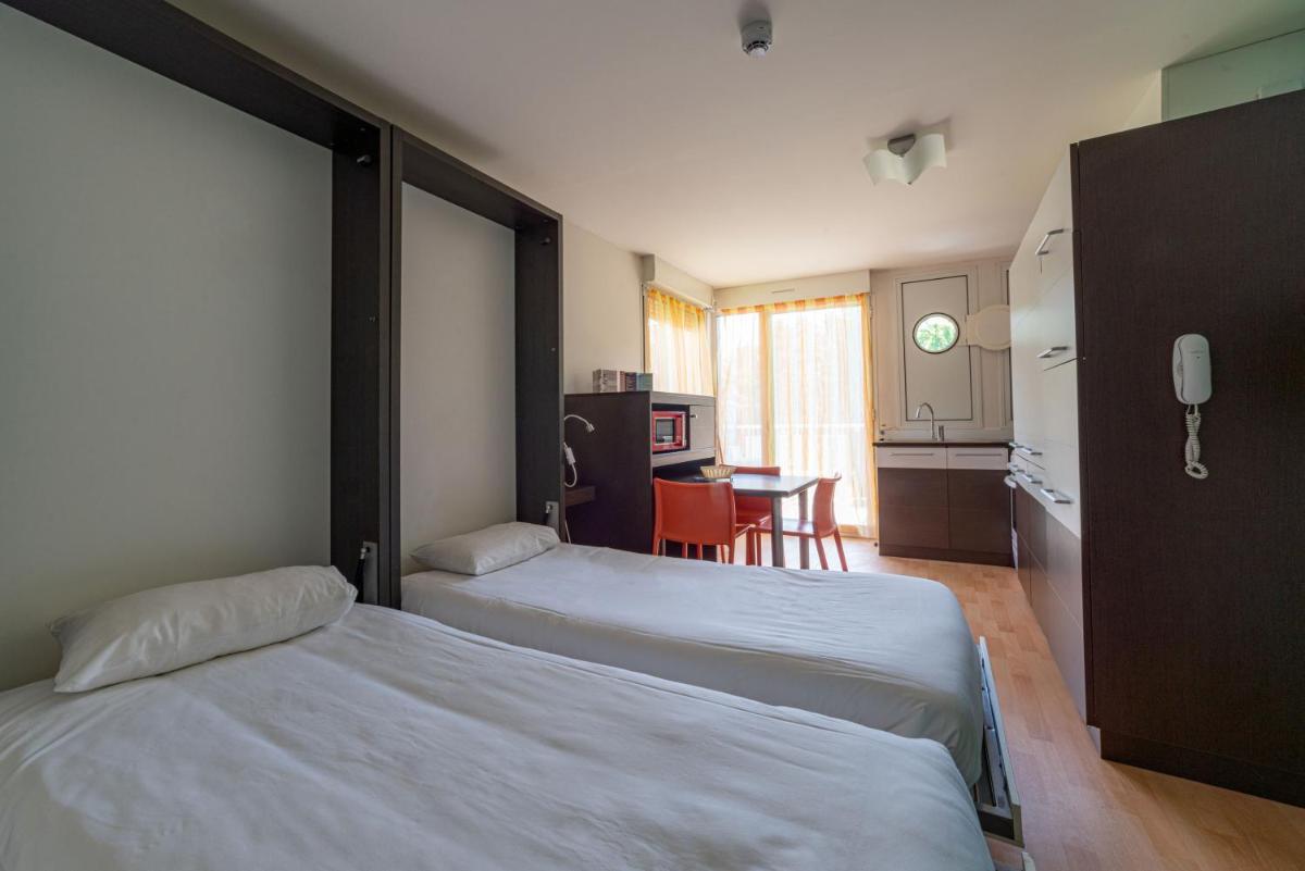 une chambre d'hôtel avec deux lits et une cuisine dans l'établissement Residence RADIANA, à La Léchère 25 autres photos