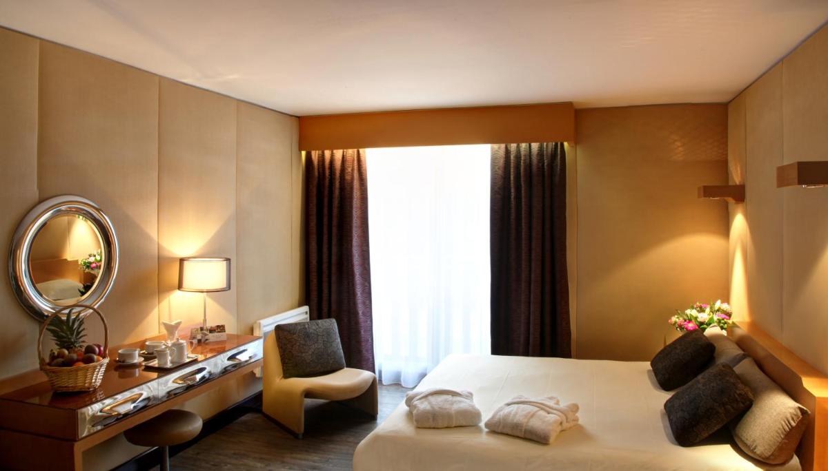 une chambre d'hôtel avec un lit et un miroir dans l'établissement Amirauté Hôtel Golf Deauville, à Deauville