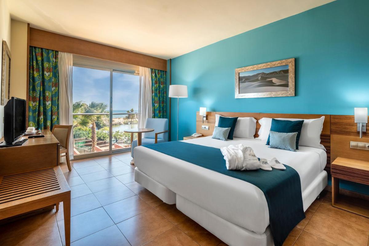Una habitación de hotel con una cama grande y un televisor. en Elba Carlota Beach & Golf Resort, en Caleta de Fuste