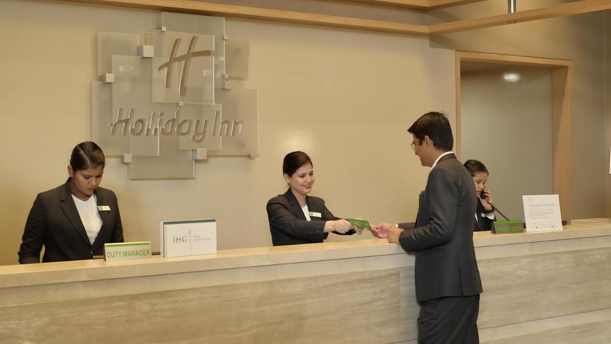 a group of people standing at a hotel counter at Holiday Inn Chennai OMR IT Expressway by IHG in Chennai