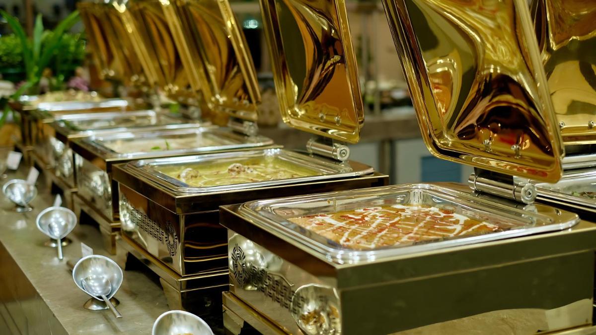 a row of gold trays of food on a table at Holiday Inn Chennai OMR IT Expressway by IHG in Chennai