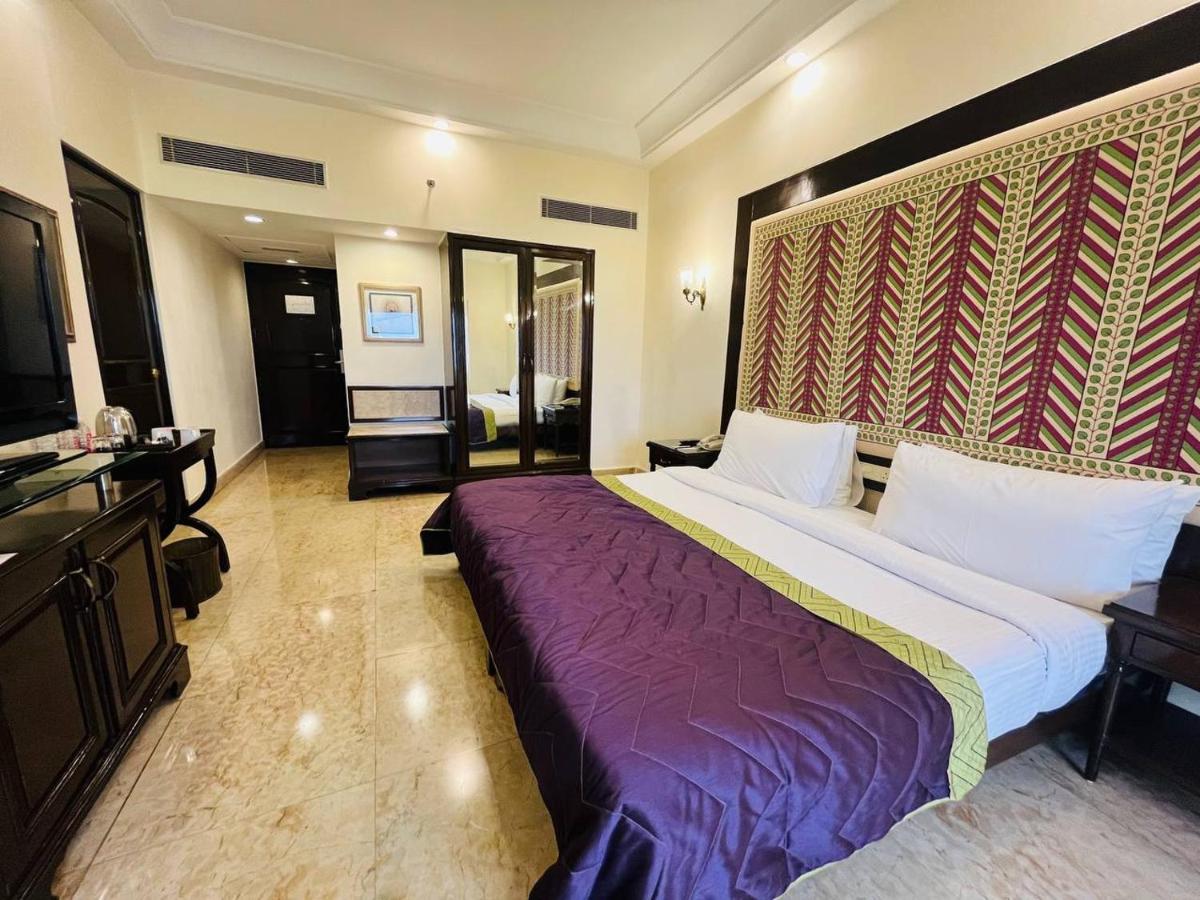 a hotel room with a large bed and a television at The Lalit Laxmi Vilas Palace in Udaipur