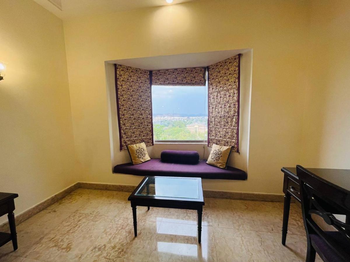 a living room with a purple couch in front of a window at The Lalit Laxmi Vilas Palace in Udaipur