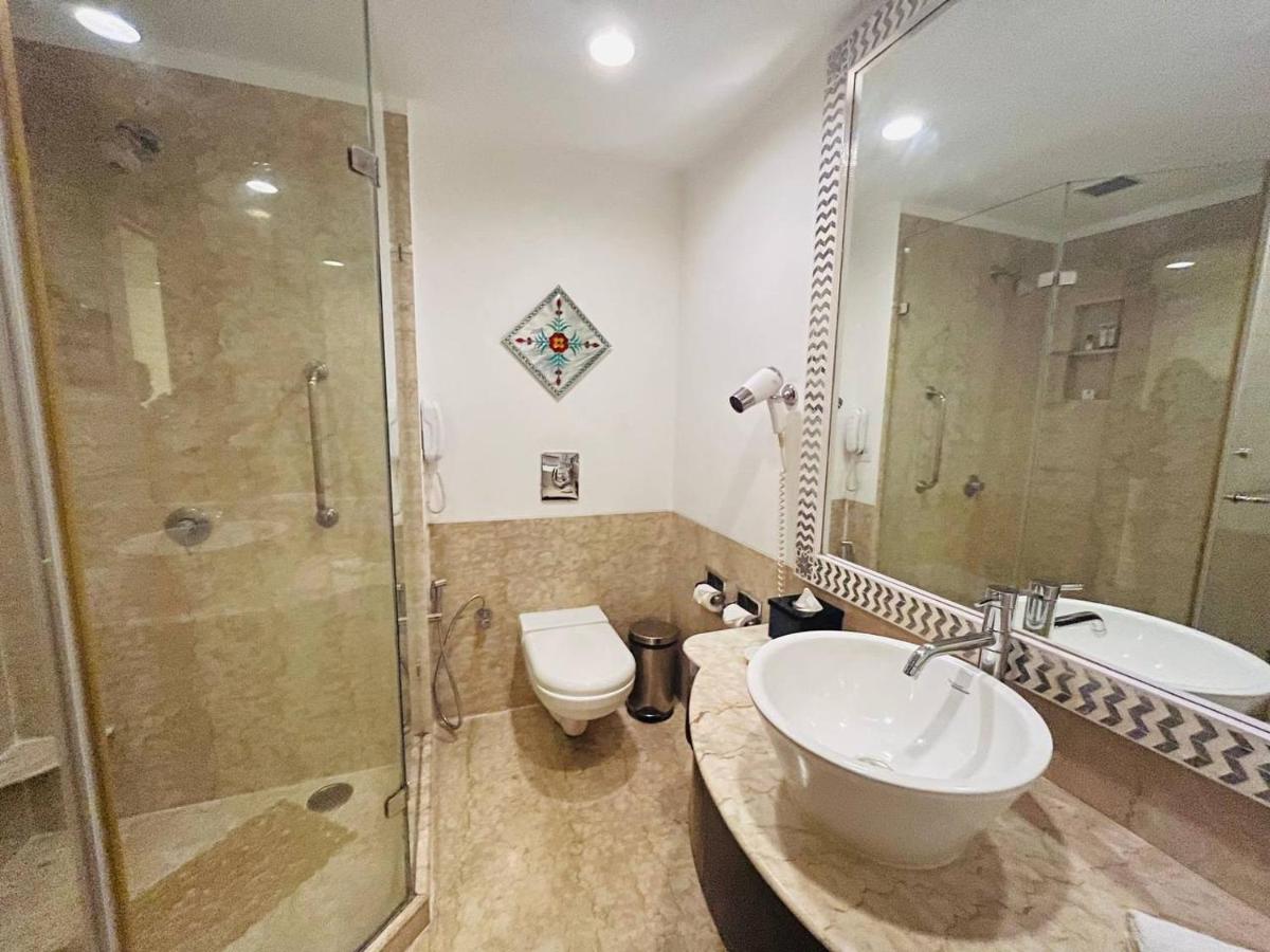 a bathroom with a sink and a shower and a toilet at The Lalit Laxmi Vilas Palace in Udaipur