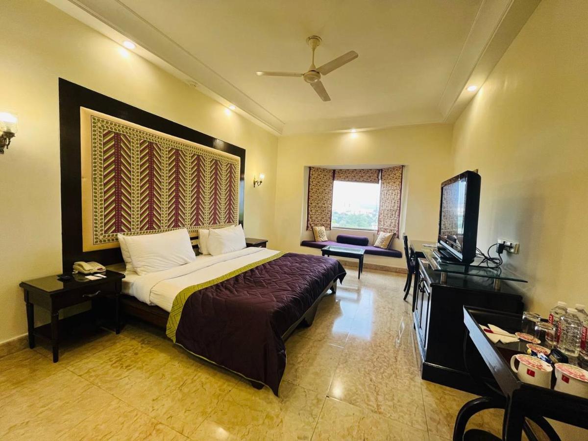 a hotel room with a bed and a television at The Lalit Laxmi Vilas Palace in Udaipur