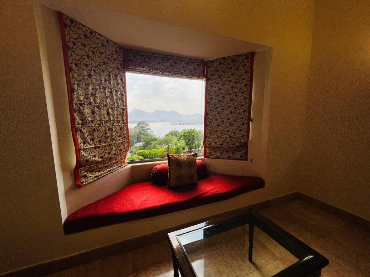 a window seat with a red bench in a room at The Lalit Laxmi Vilas Palace in Udaipur