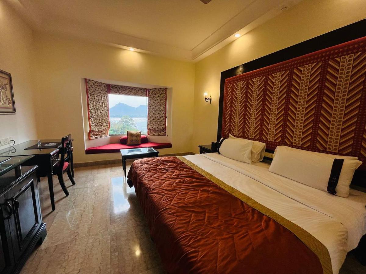 a hotel room with a large bed and a desk at The Lalit Laxmi Vilas Palace in Udaipur