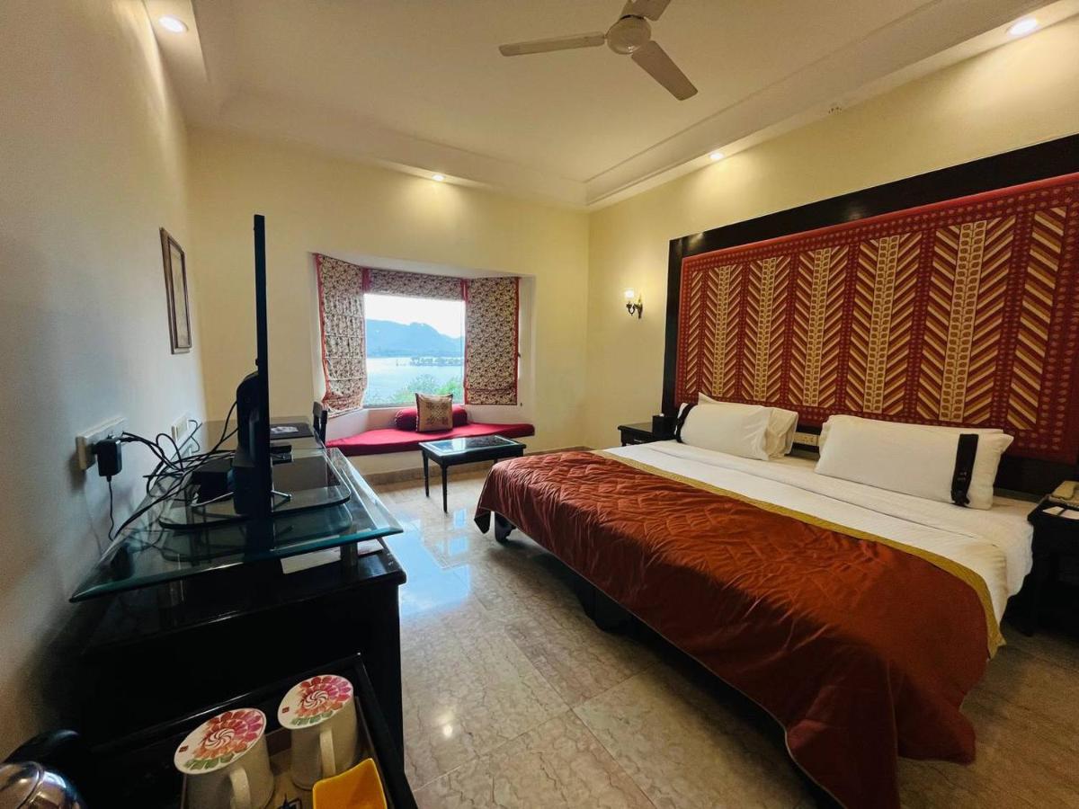 a bedroom with a large bed with a red blanket at The Lalit Laxmi Vilas Palace in Udaipur