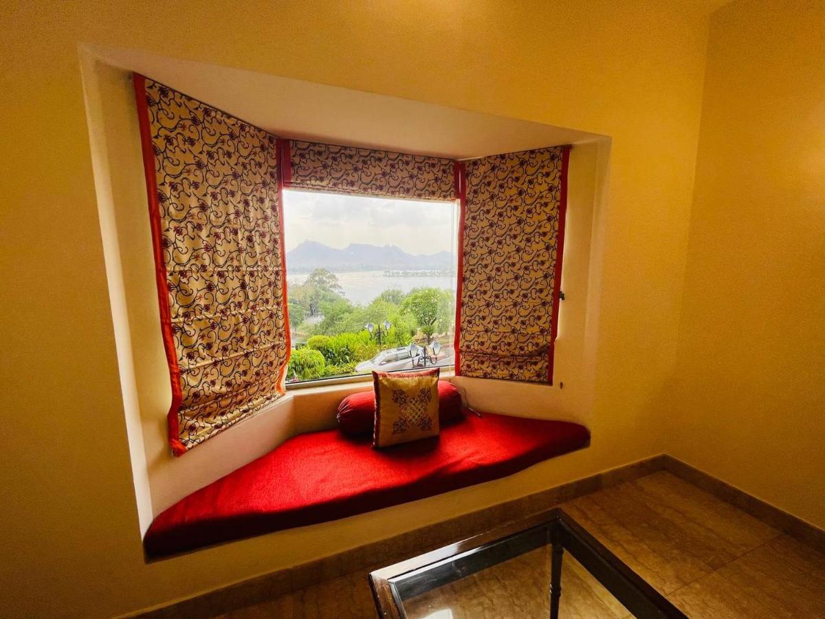 a window seat with a red bench in front of a window at The Lalit Laxmi Vilas Palace in Udaipur