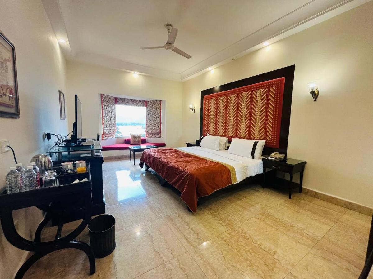 a bedroom with a bed and a desk and a piano at The Lalit Laxmi Vilas Palace in Udaipur