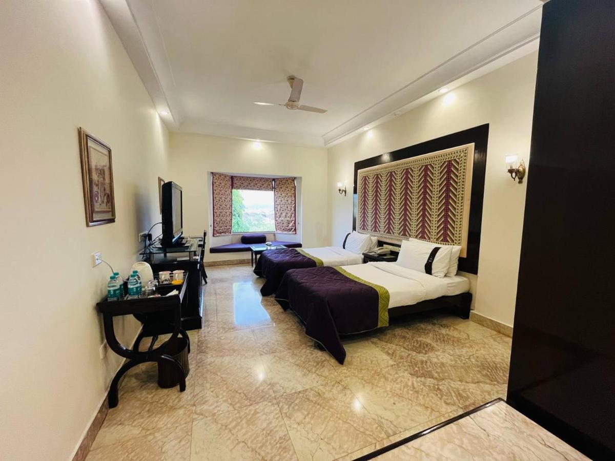 a hotel room with a bed and a desk at The Lalit Laxmi Vilas Palace in Udaipur