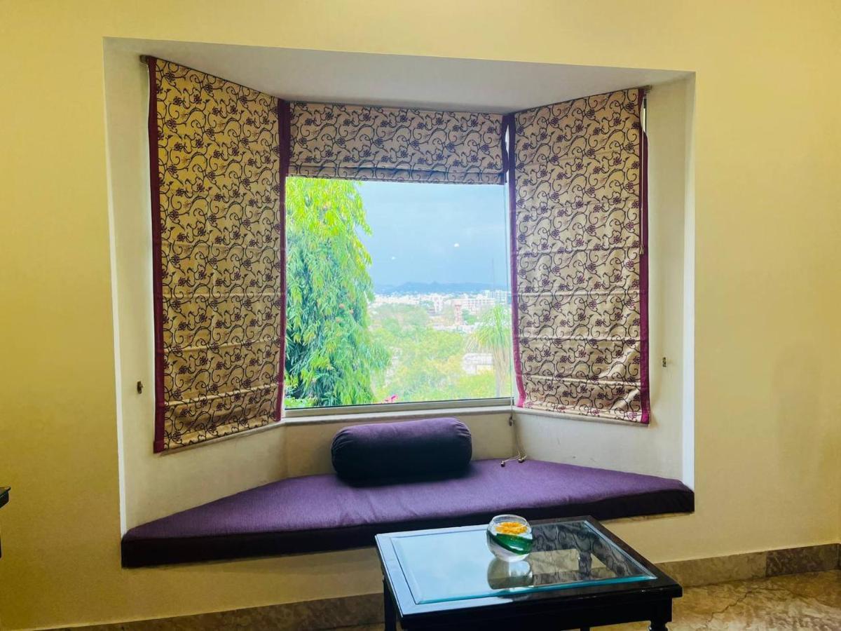 a window with a purple couch in a room with a table at The Lalit Laxmi Vilas Palace in Udaipur