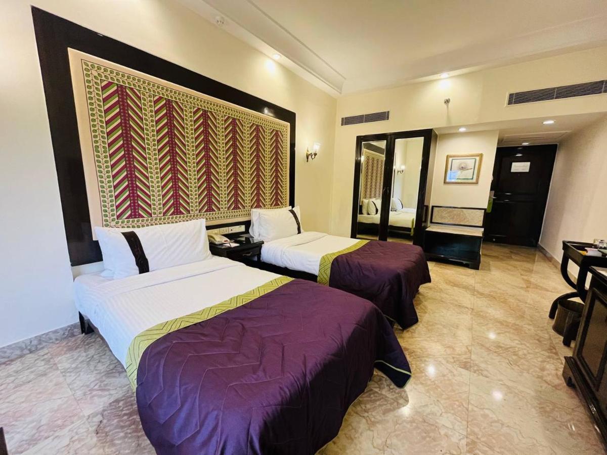 a hotel room with two beds with purple sheets at The Lalit Laxmi Vilas Palace in Udaipur