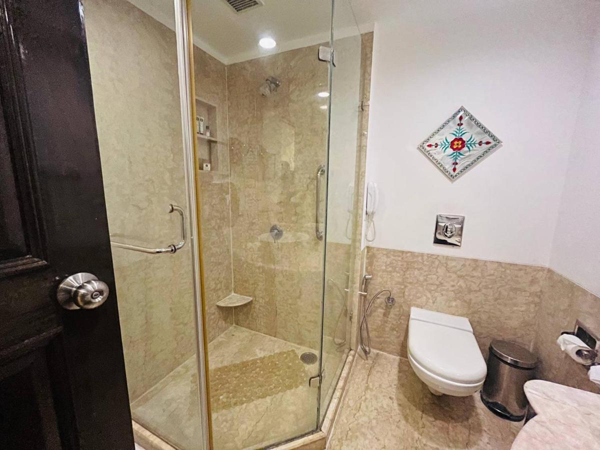 a bathroom with a glass shower and a toilet at The Lalit Laxmi Vilas Palace in Udaipur