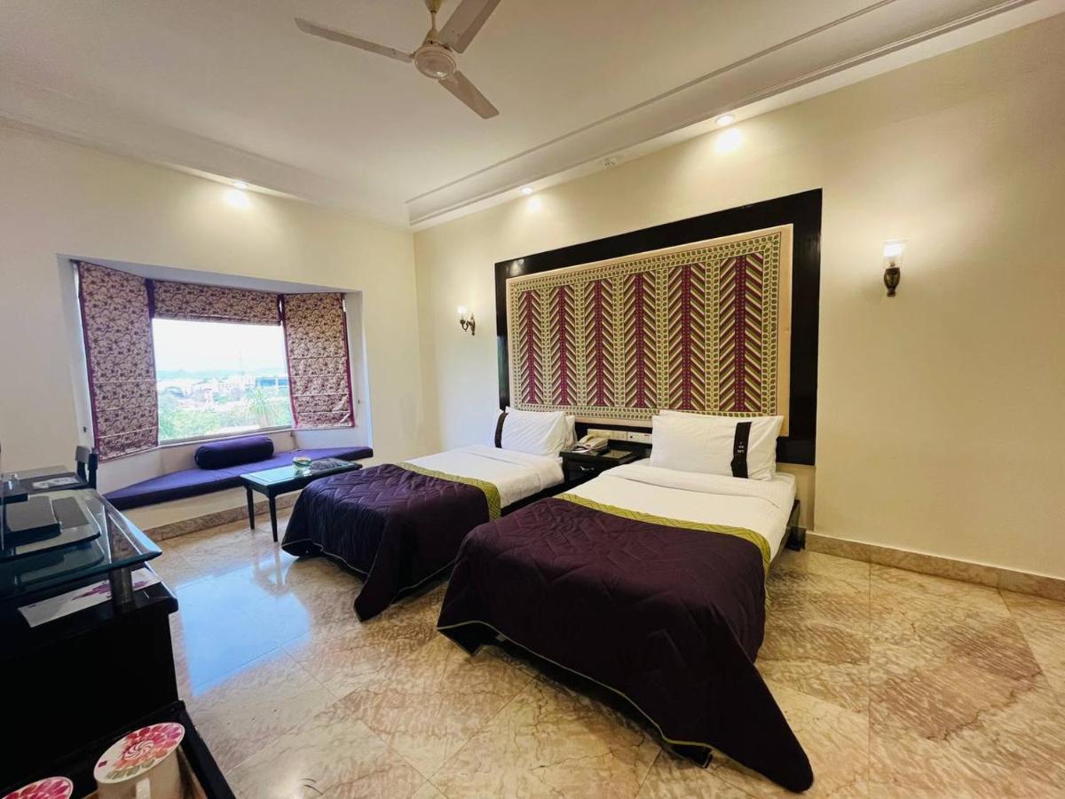 a hotel room with two beds and a window at The Lalit Laxmi Vilas Palace in Udaipur