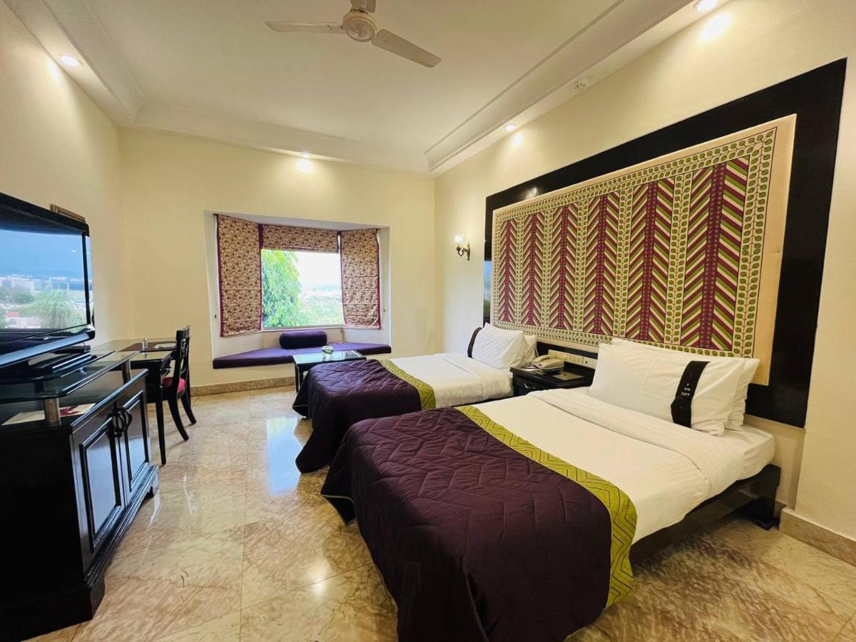 a hotel room with two beds and a flat screen tv at The Lalit Laxmi Vilas Palace in Udaipur