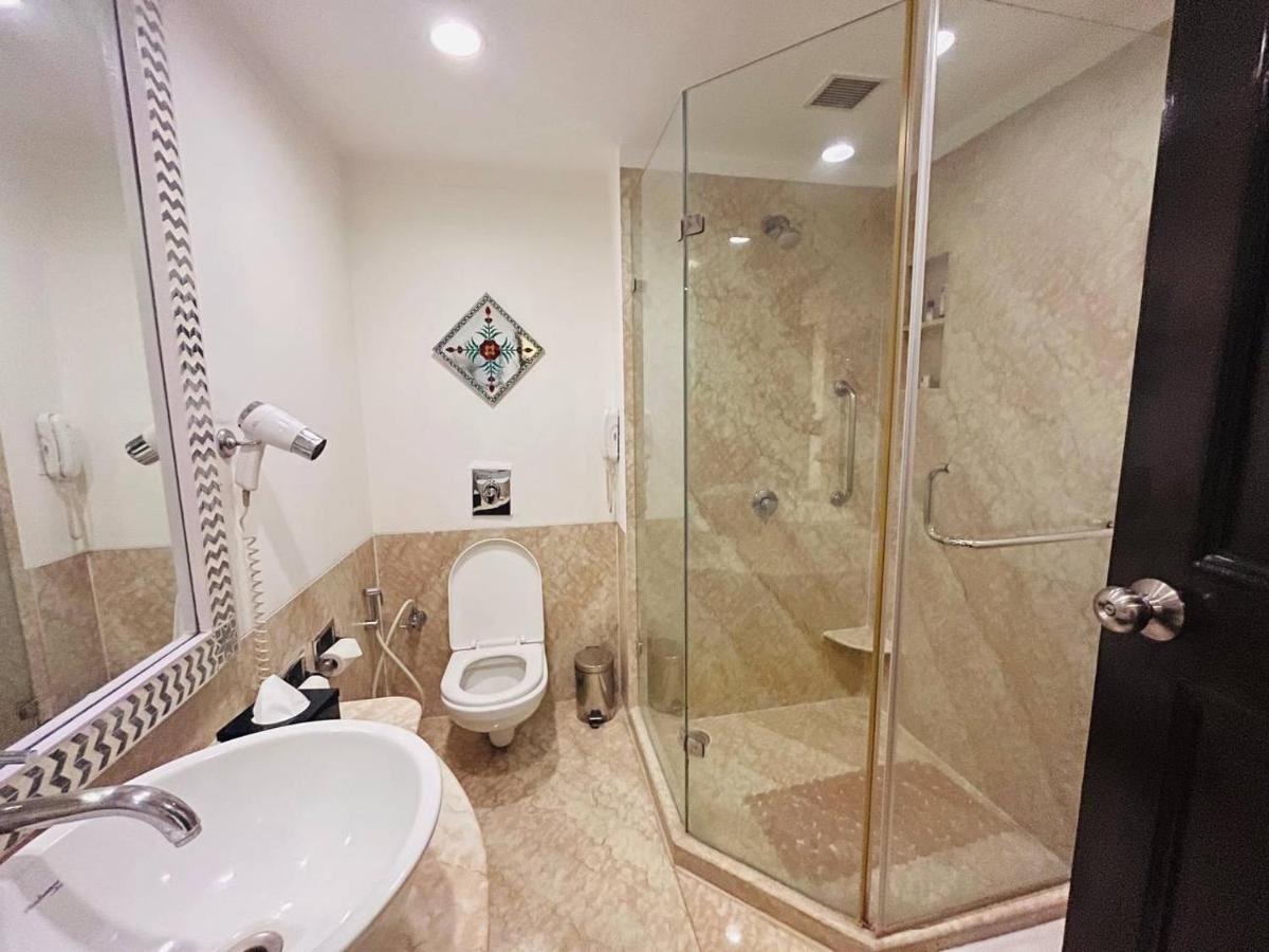 a bathroom with a toilet and a glass shower at The Lalit Laxmi Vilas Palace in Udaipur