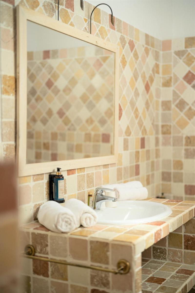 une salle de bain avec un lavabo, un miroir et des serviettes dans l'établissement Hôtel Le Mas des Grès & Restaurant Sous les Platanes, à Lagnes