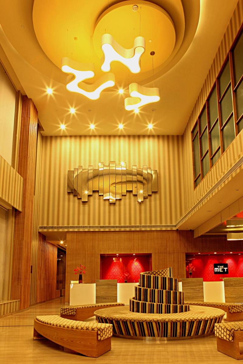 a lobby with chairs and a chandelier in a building at The Metropolitan Hotel & Spa New Delhi in New Delhi