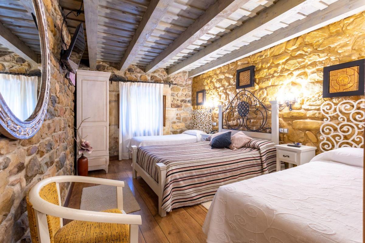 Un dormitorio con dos camas y una pared de piedra. en Hotel Spa Casona La Hondonada, en Terán