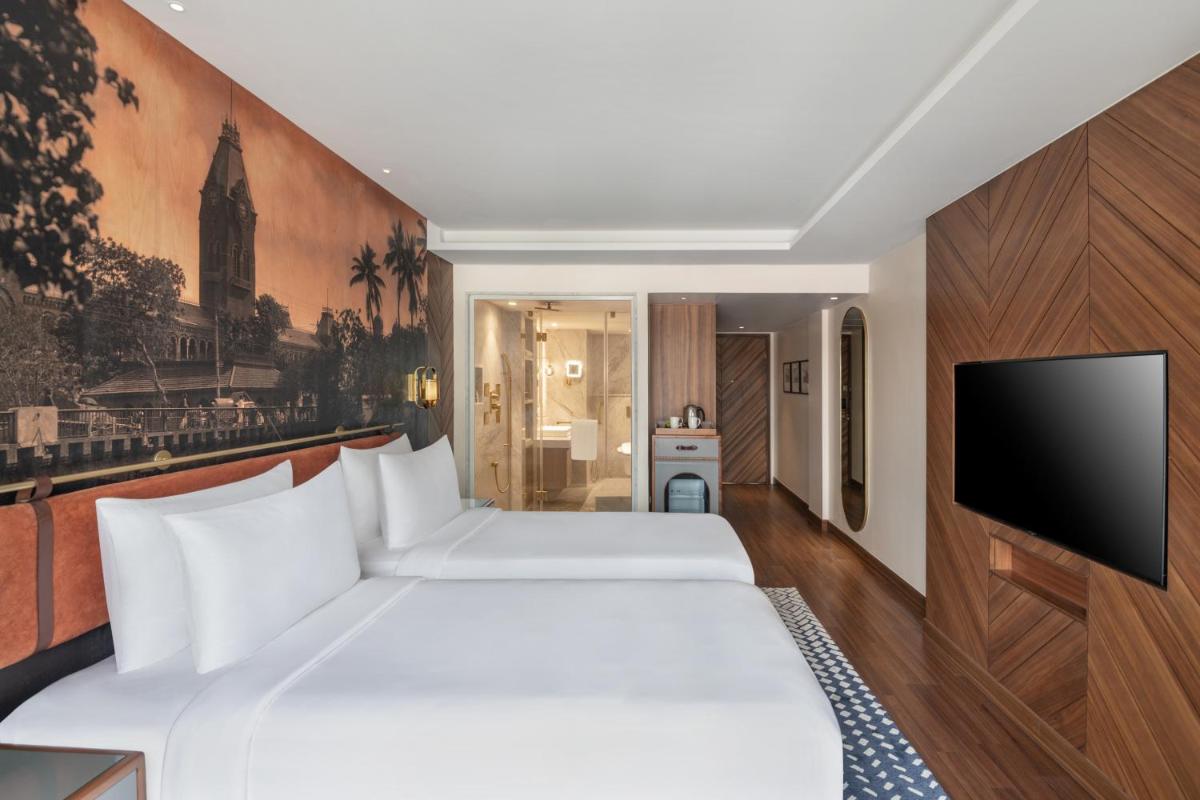 a bedroom with a large white bed and a flat screen tv at Radisson Blu Hotel & Suites GRT Chennai in Chennai