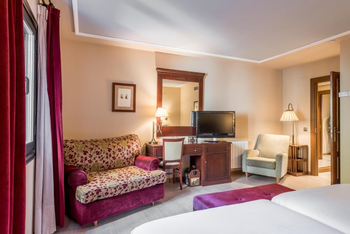 Habitación de hotel con sillón y TV en Snö Villa de Sallent 4, en Formigal