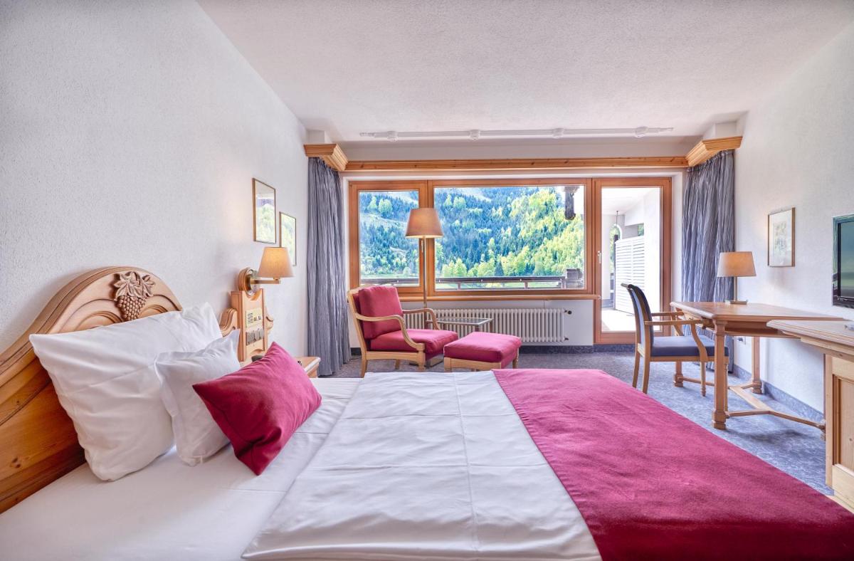 ein Hotelzimmer mit einem großen Bett und einem Schreibtisch in der Unterkunft Hotel Traube Tonbach in Baiersbronn