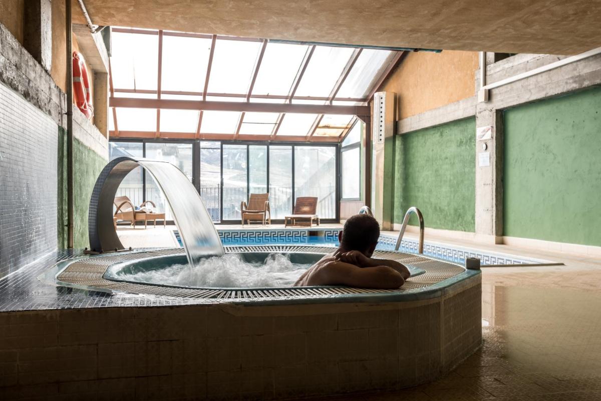 una persona en una bañera de hidromasaje con una fuente de agua en Snö Villa de Sallent 4, en Formigal