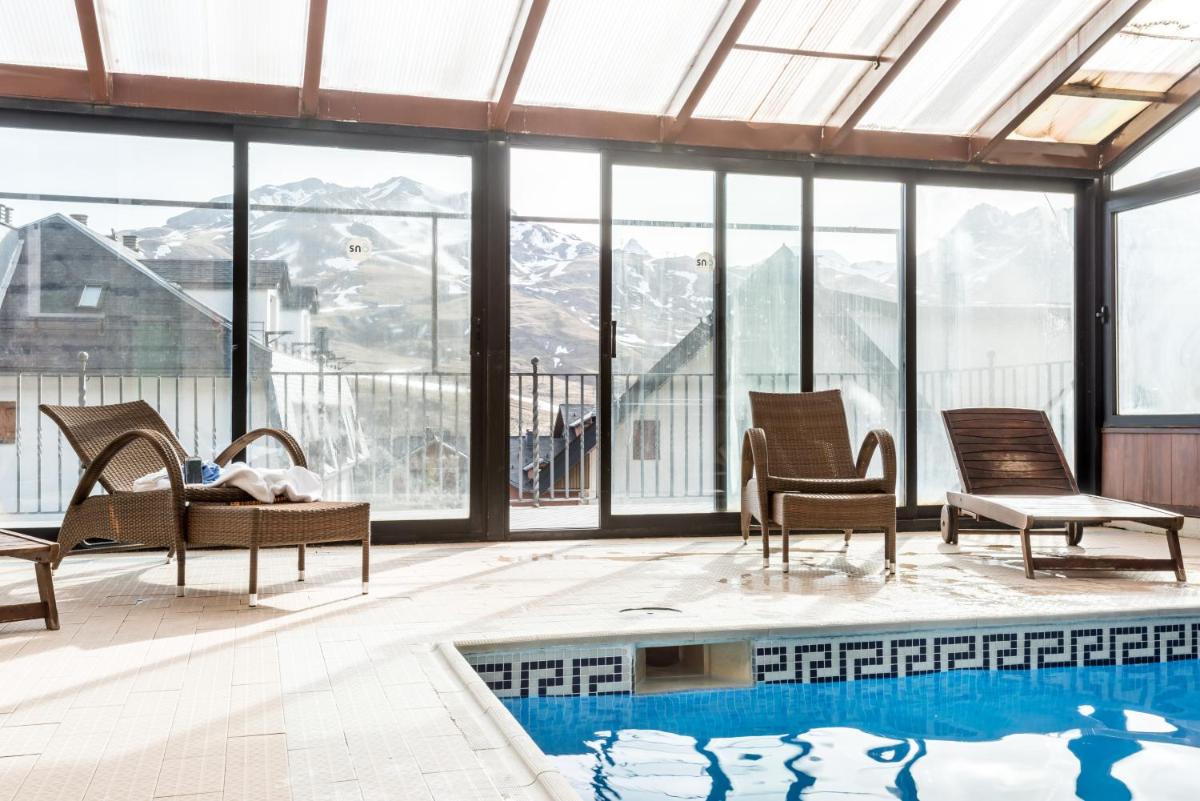 Habitación con sillas, piscina y ventanas en Snö Villa de Sallent 4, en Formigal