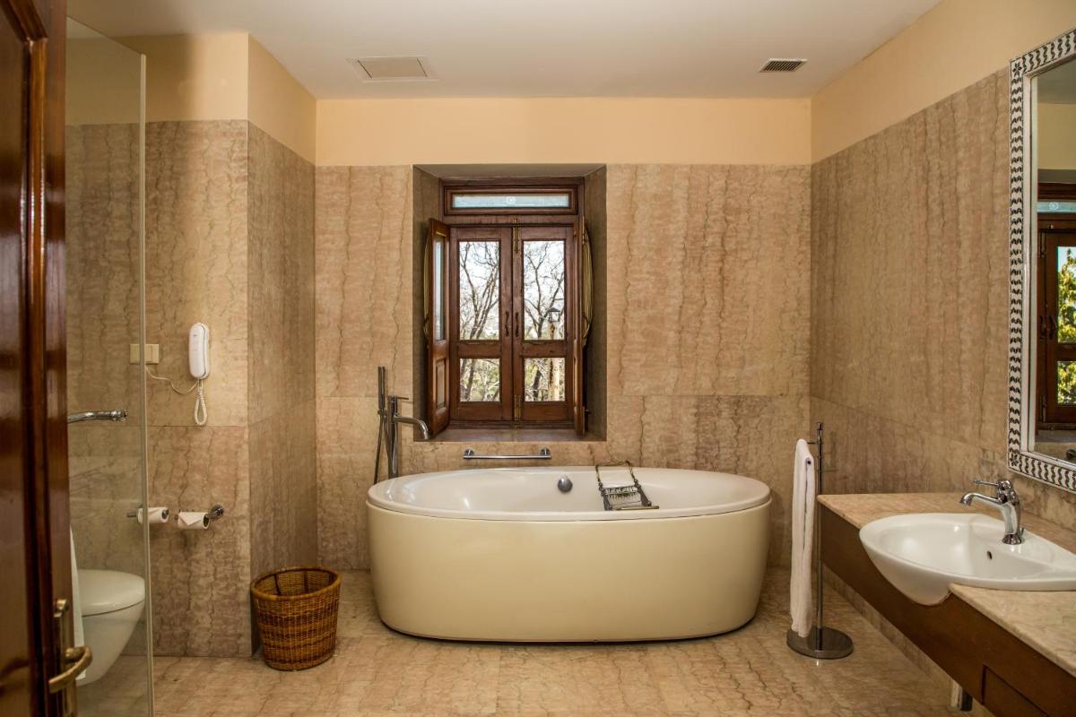 a bathroom with a tub and two sinks and a window at The Lalit Laxmi Vilas Palace in Udaipur