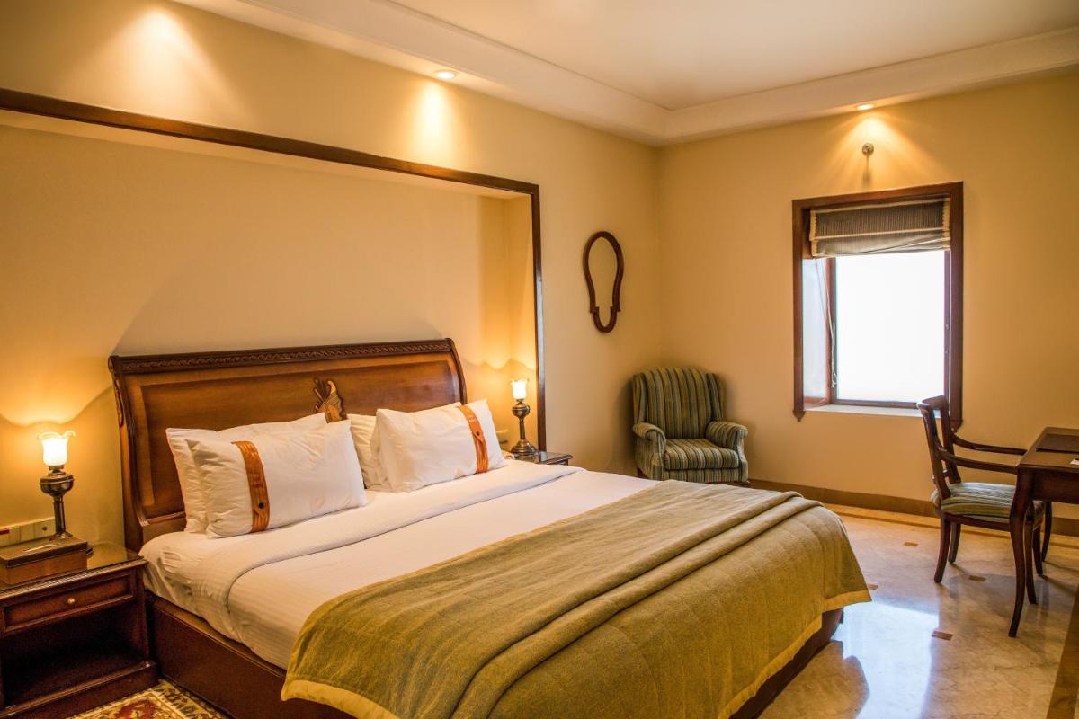 a hotel room with a large bed and a chair at The Lalit Laxmi Vilas Palace in Udaipur
