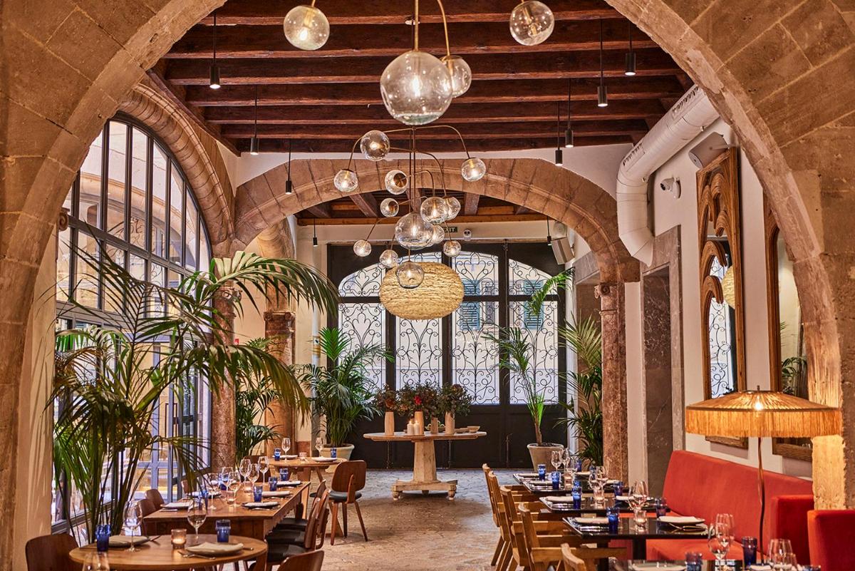 Un restaurante con mesas y sillas de madera y ventanas. en Puro Grand Hotel, en Palma de Mallorca