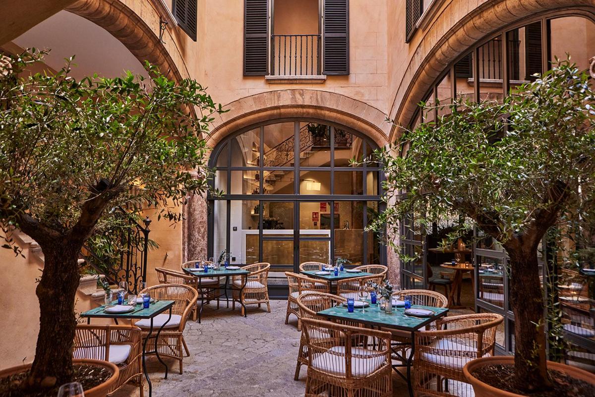 Un patio al aire libre con mesas, sillas y árboles. en Puro Grand Hotel, en Palma de Mallorca