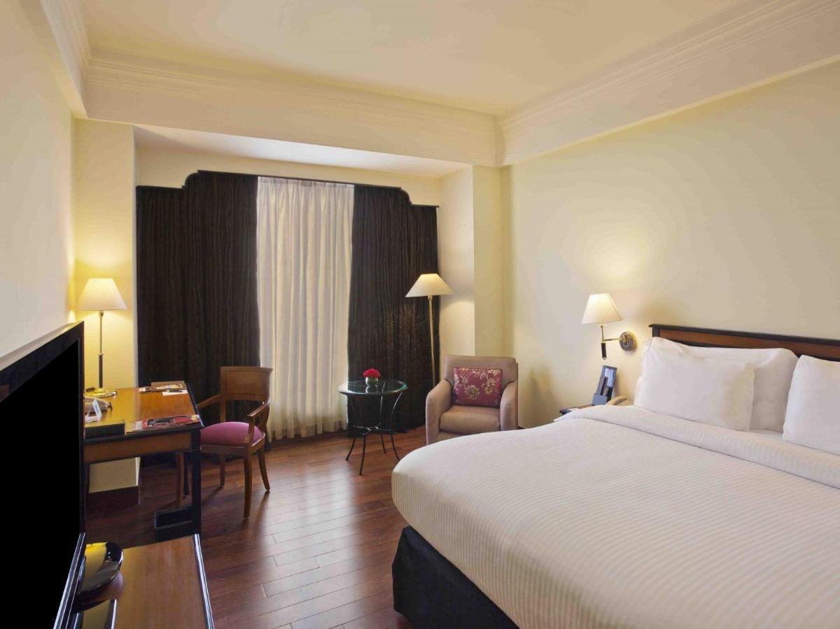 a hotel room with a bed and a desk at Eros Hotel New Delhi, Nehru Place in New Delhi a hotel room with a bed and a desk at Eros Hotel New Delhi, Nehru Place in New Delhi