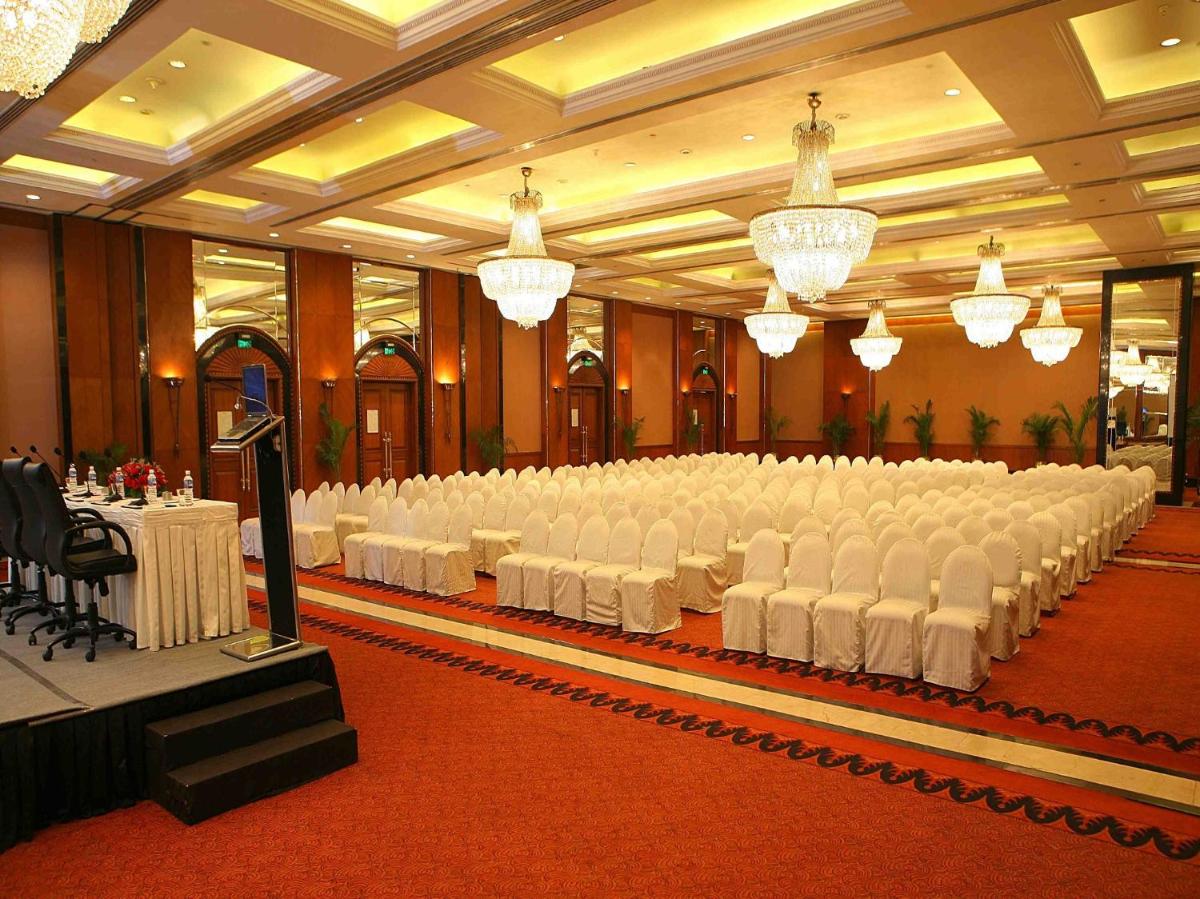 a banquet hall with white chairs and tables and chandeliers at Eros Hotel New Delhi, Nehru Place in New Delhi a banquet hall with white chairs and tables and chandeliers at Eros Hotel New Delhi, Nehru Place in New Delhi