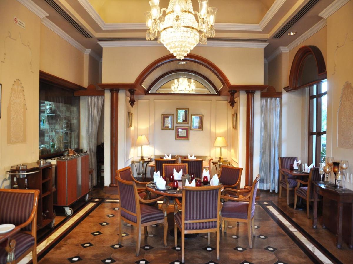 a dining room with a table and chairs and a chandelier at Eros Hotel New Delhi, Nehru Place in New Delhi a dining room with a table and chairs and a chandelier at Eros Hotel New Delhi, Nehru Place in New Delhi
