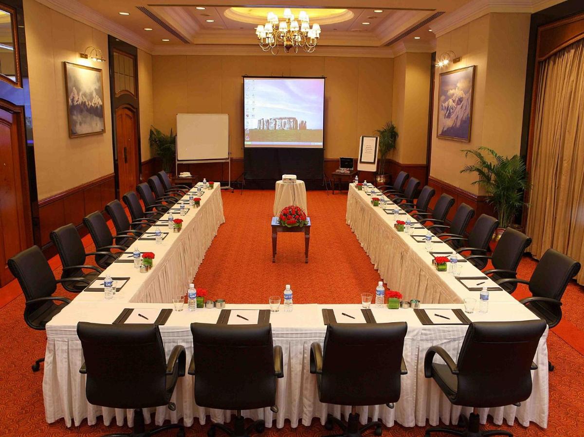 a meeting room with long tables and chairs and a screen at Eros Hotel New Delhi, Nehru Place in New Delhi a meeting room with long tables and chairs and a screen at Eros Hotel New Delhi, Nehru Place in New Delhi