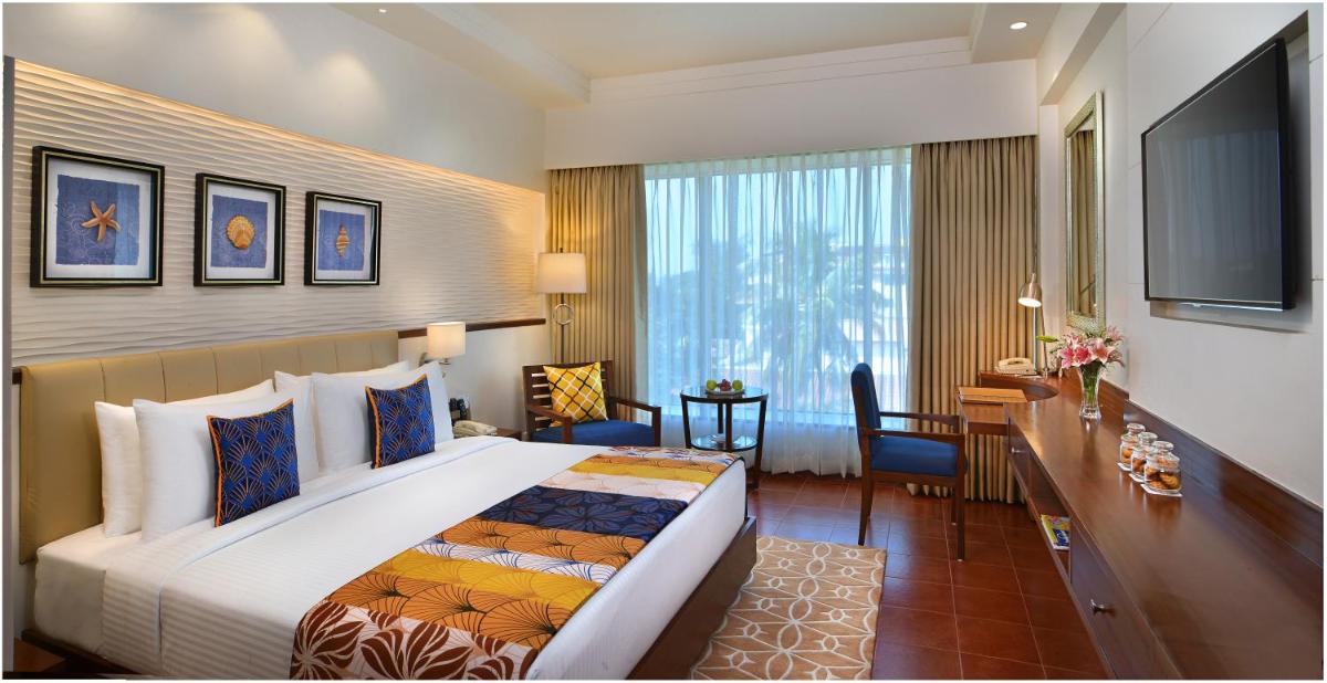 a hotel room with a large bed and a desk at Fortune Miramar, Goa - Member ITC Hotels' Group in Panaji a hotel room with a large bed and a desk at Fortune Miramar, Goa - Member ITC Hotels' Group in Panaji