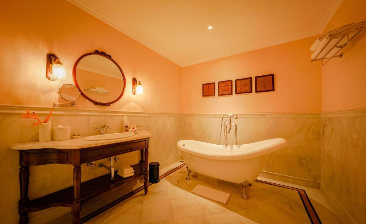 a bathroom with a tub and a sink and a mirror at Raajkutir - IHCL SeleQtions in Kolkata